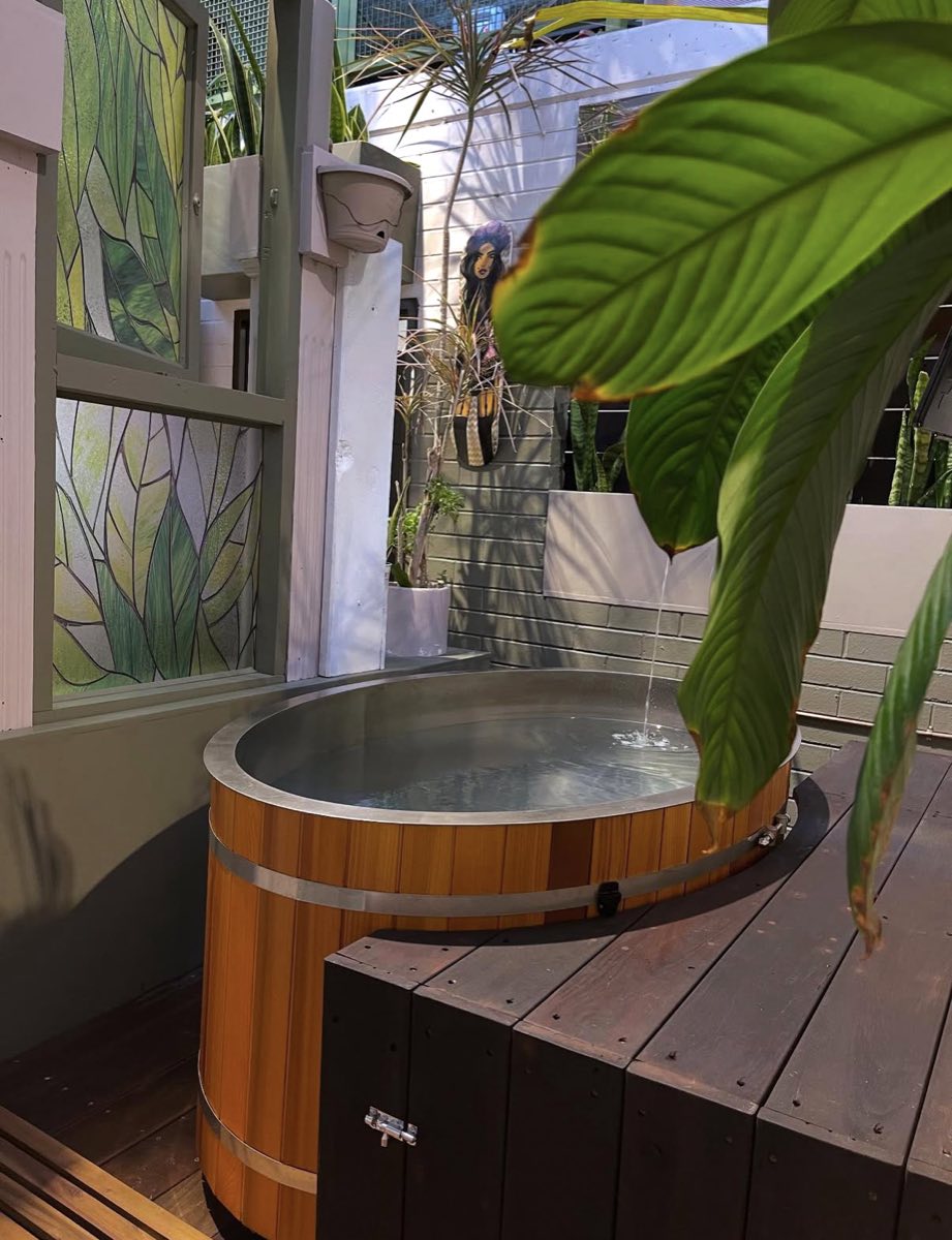 Cedar-clad bath on the timber deck, framed by broad green leaves