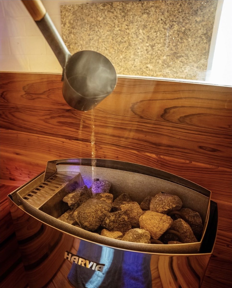 Steam rising from hot sauna rocks as water is poured on